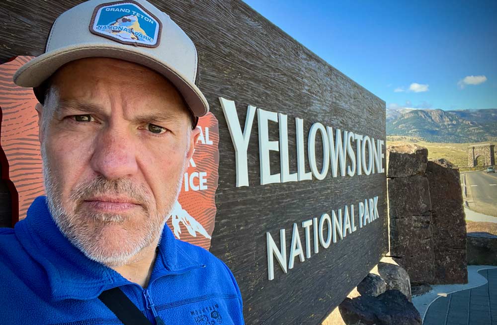 Me standing at the entrance sign for Yellowstone National Park in Gardiner, Montana